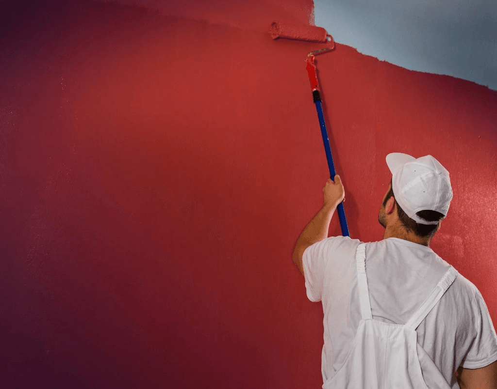 Painter rolling red paint onto an interior wall